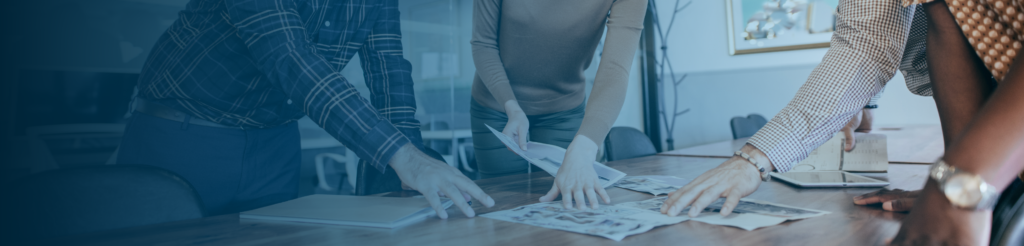 Three professionals reviewing documents and discussing workforce setup options at a meeting table.