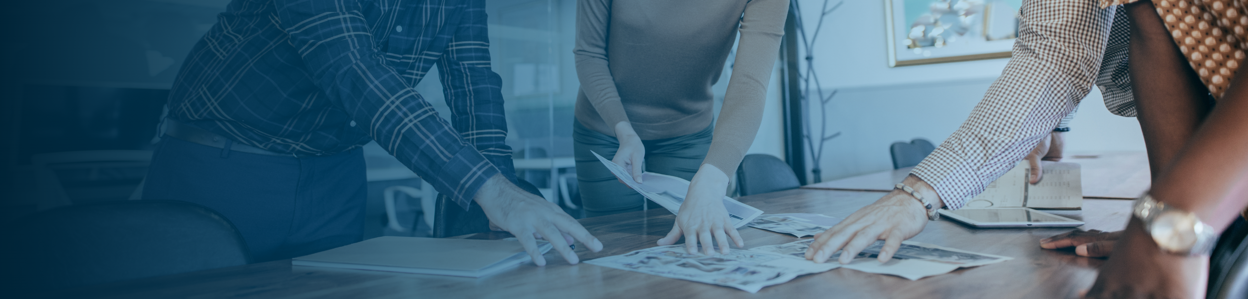 Three professionals reviewing documents and discussing workforce setup options at a meeting table.